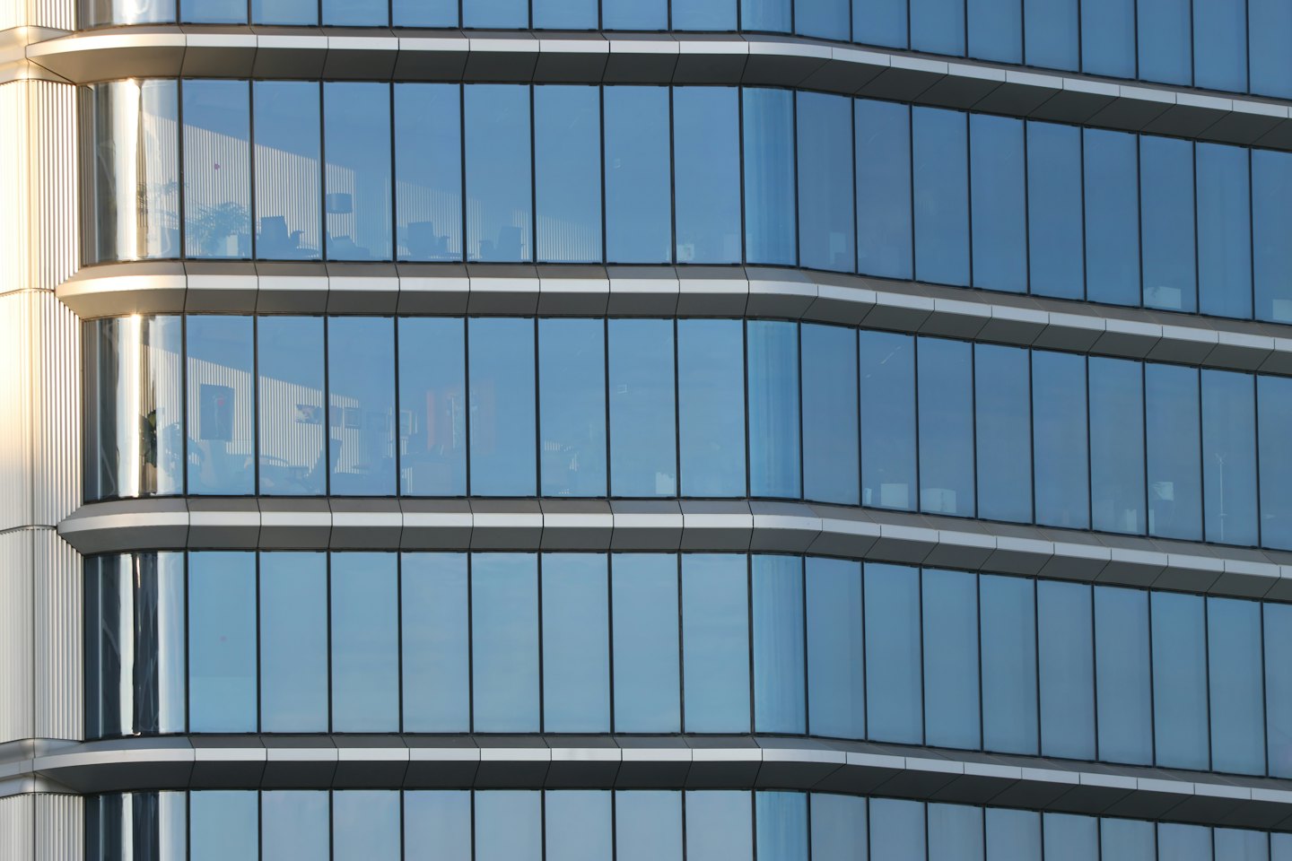 Fachada de edificio de oficinas curvilíneo con ventanas de cristal azul reflectante.