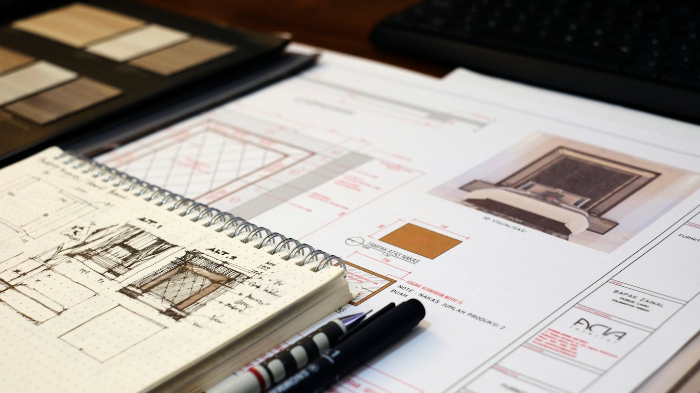 Planos arquitectónicos y bocetos sobre un escritorio de madera.