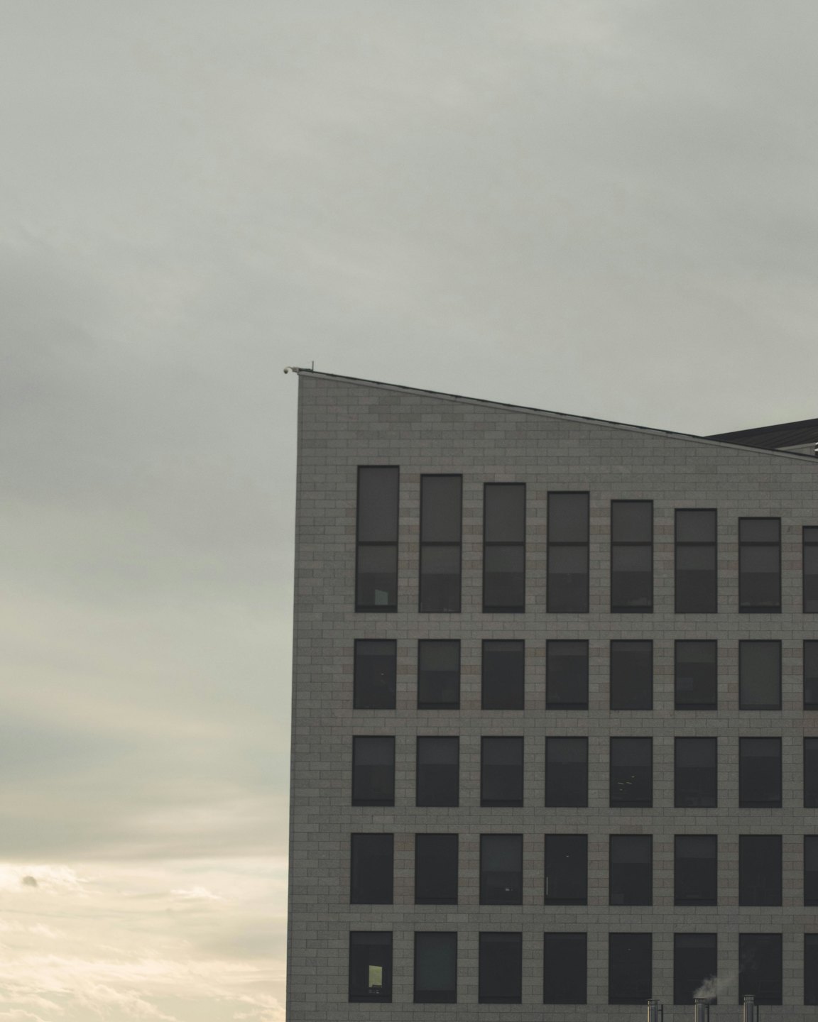 Edificio comercial moderno de ladrillo gris con techo inclinado.